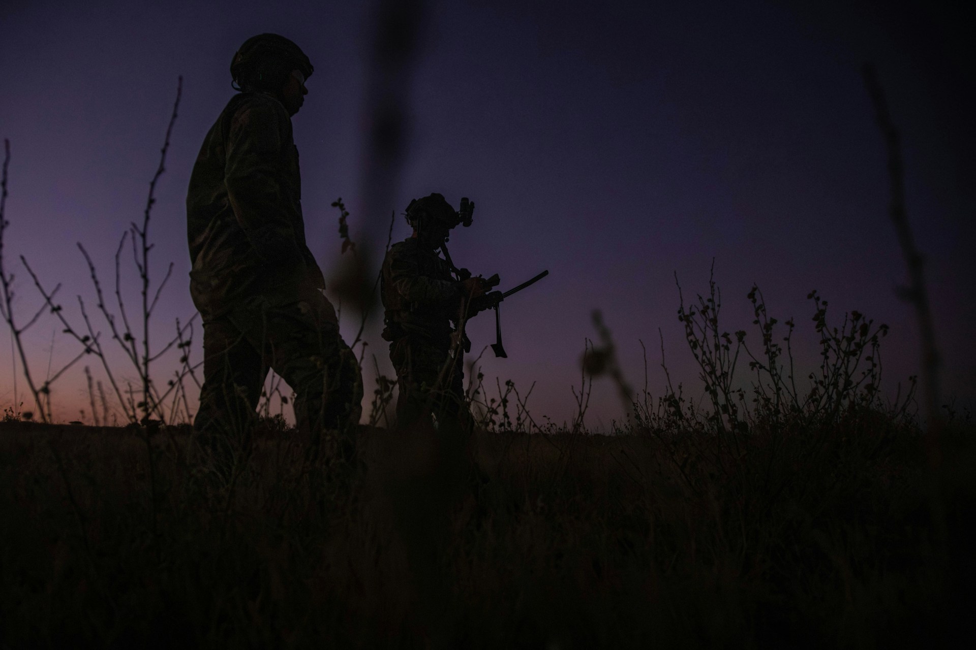 Two soldiers walking through a field at dusk